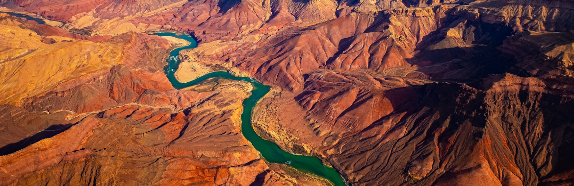 A panoramic landscape view of a curving Colorado River running through the Grand Canyon. Distinguished Fellows